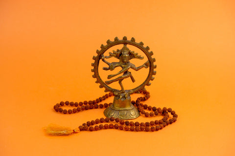 Hindu's Lord Shiva depicted in a brass sculpture. He is dancing in the center, surrounded by a circle.