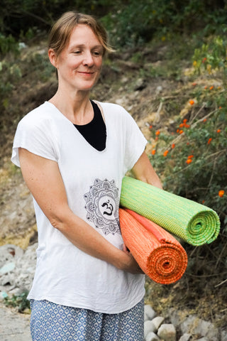 Sophia holding rolled up organic cotton yoga mats.