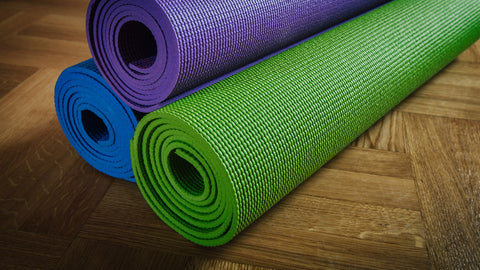 Conventional yoga mats rolled up on the floor.