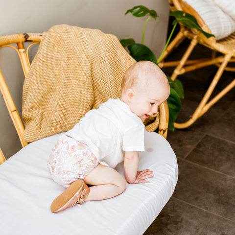 Small toddler wearing a hand illustrated modern cloth nappy with a pastel pink peony pattern