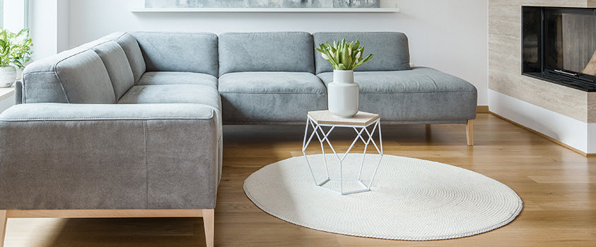 An ivory-coloured flatweave area floor rug in a round shape helps draw attention to the uniquely designed centre table. 
