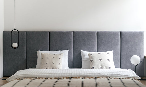 A grey fabric upholstery bedhead in king size against a white wall creates a modern look and laid-back vibe. 