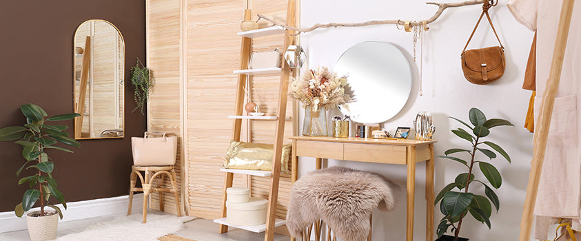 A boho aesthetic bedroom that heavily features wood furniture and decor, tied together with a simple wood vanity and a footstool with a fur cover.