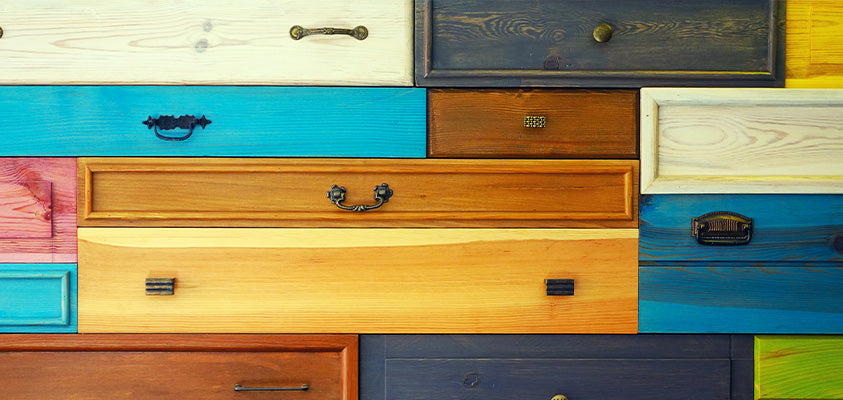 A close up of wooden drawers with various colours and fittings pressed together.