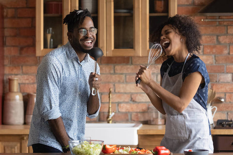 couple cooking together while singing from a music playlist