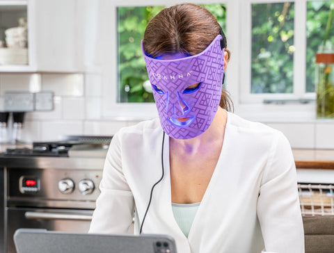 Woman working on computer while using the blue light of the LED mask