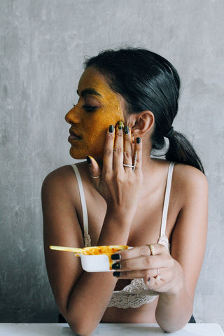 Lady applying turmeric and honey face mask