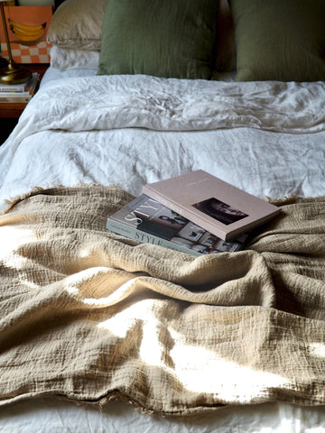 Linen Bed Throw styled on the edge of a bed on rustic linen bedding. Books on top of the bed throw for a styled aesthetic.