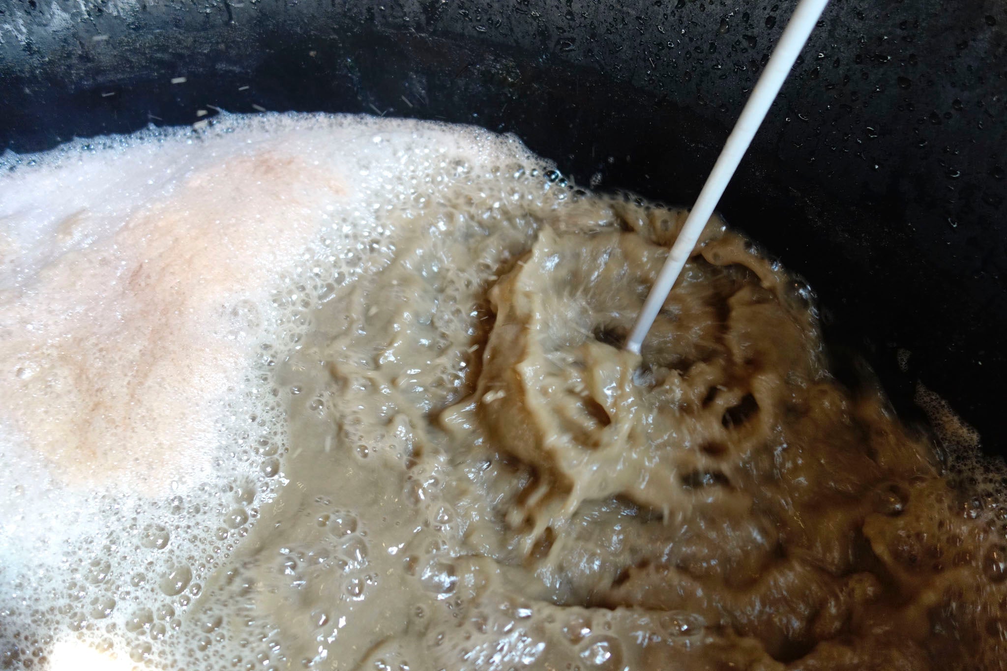 Whipping up the hydrated lime into the water of the indigo extraction vat at Okan Arts