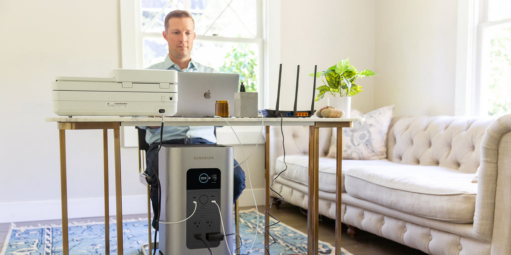 A man works at a desk in a home office powered by the HomePower backup battery power station.