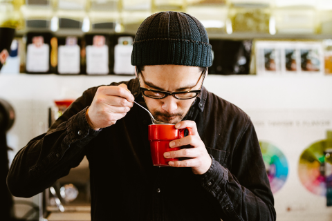 A photo of a man tasting coffee.