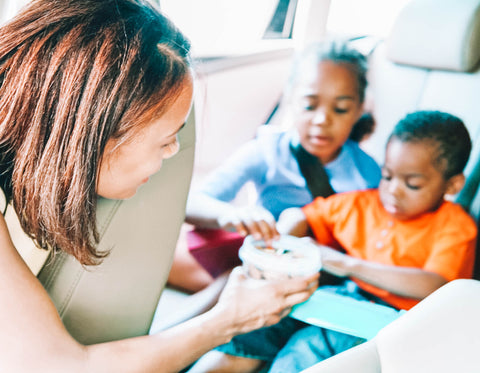 Mom Feeding Kids Snacks In The Back Seat