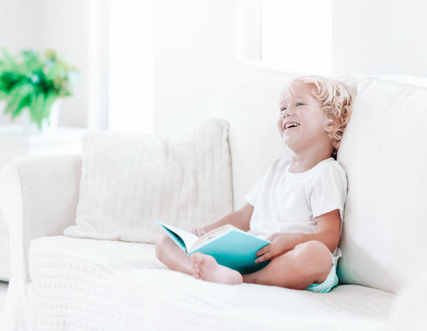 Child Reading Book on Couch