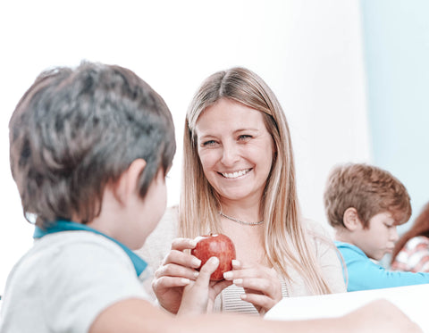 Student handing teacher an apple