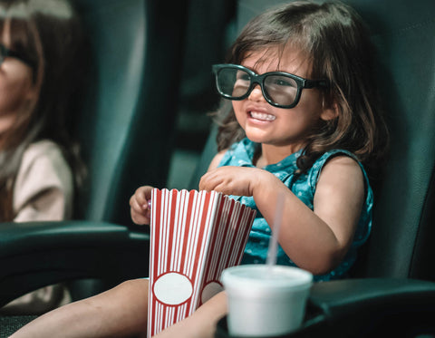 little girl with popcorn in movie theater