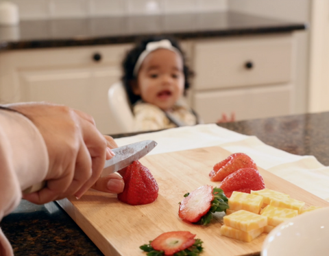 Mom Cutting Strawberries and Cheese while Toddler Watches from Baby Basics High Chair