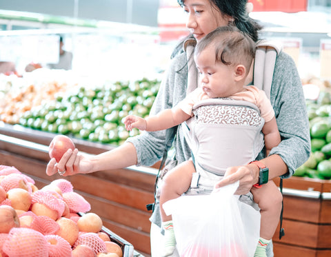 Mom looking at apples in the grocery store with baby