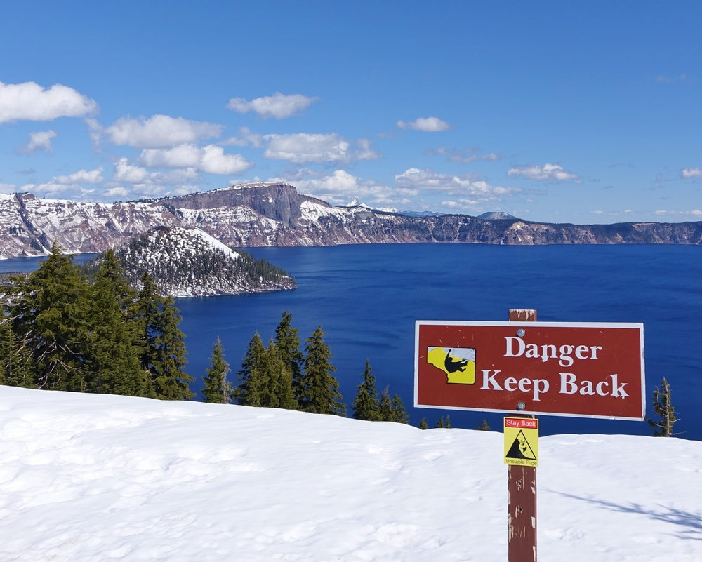 Danger Sign Along Snowy Slopes Looking Out Over Lake in Crater Lake National Park