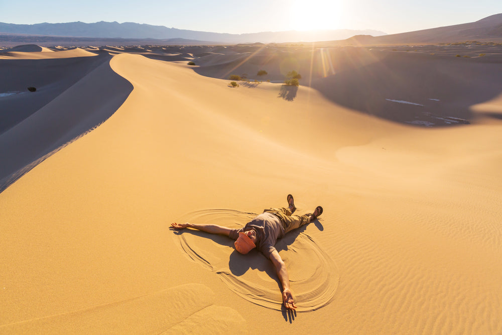 Man Making Sand Angel on Sand Dunes in Death Valley National Park California USA