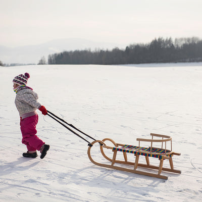 little girl walking sled on her way to go sledding at Chain o’ Lakes State Park