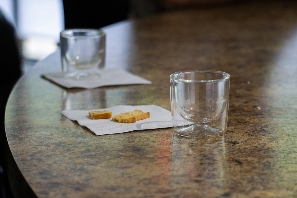 Image of 2 double walled glass tea cups and napkin with shortbread cookies on tea tasting bar