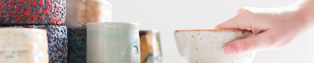 cluster of handmade clay and ceramic tea cups, matcha bowls, and other tea ware 