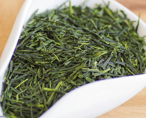 Hojas de té verde japonés Sencha en un recipiente blanco