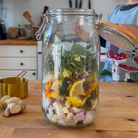 Large clear jar with fire cider ingredients inside