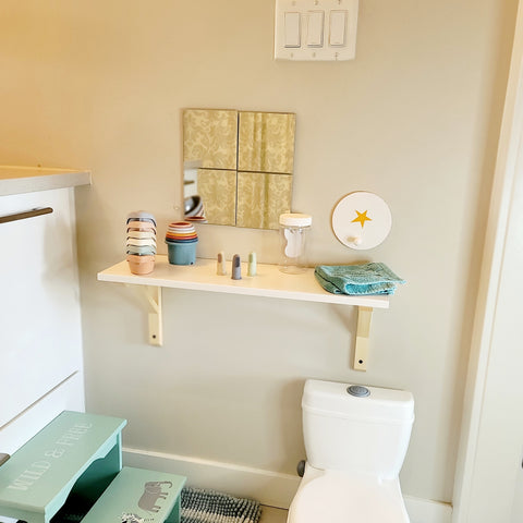 Small baby sized shelf in the bathroom of a home with baby bath toys and baby silicone finger brush in a montessori bathroom