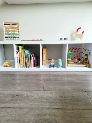 Étagère taille bébé avec jouets en bois et activités montessori dans le salon