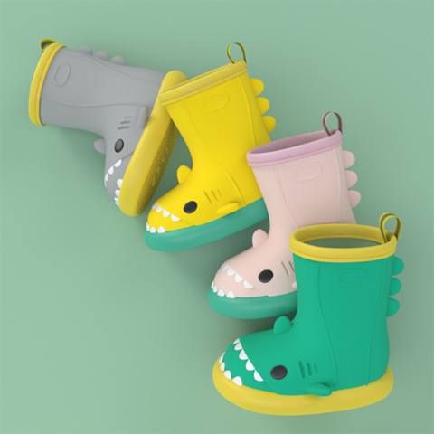 four different colors of shark rain boots laid against a green background