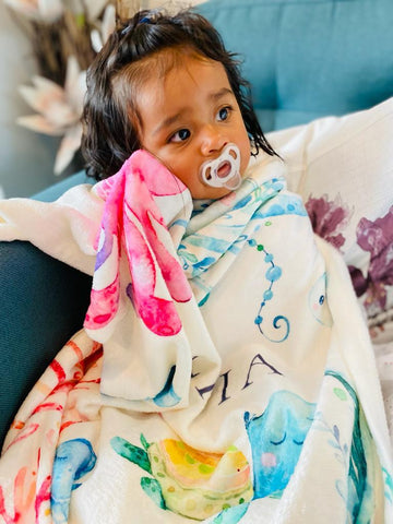 Niña sosteniendo su suave y calentita manta polar personalizada con el nombre del bebé | Hunny Bubba Niños