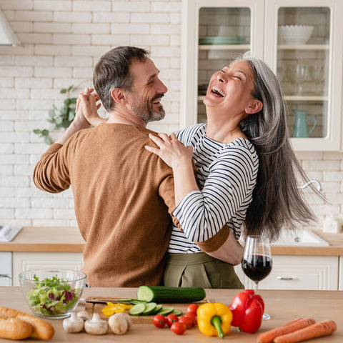 older couple dancing and laughing with fresh fruits and vegetables