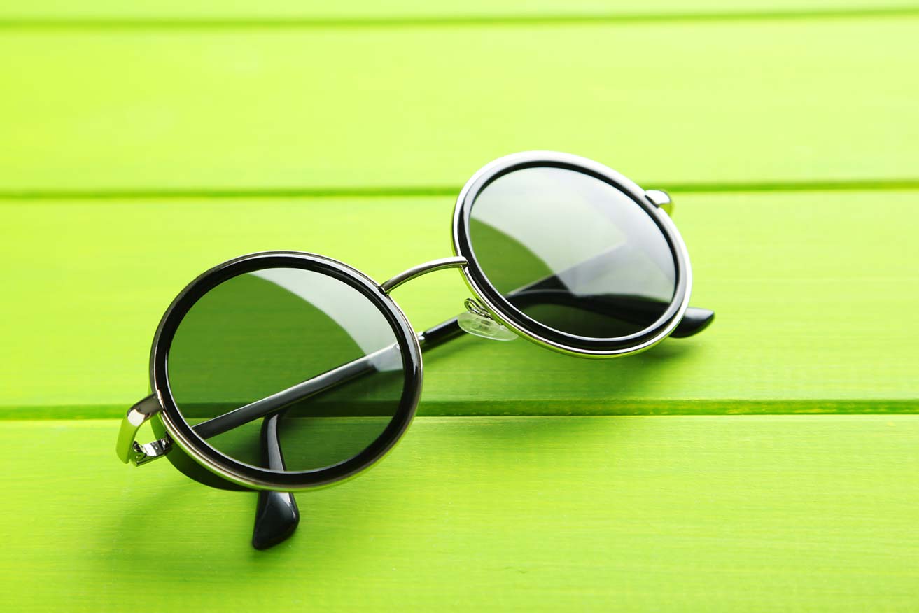 Black, rounded lens glasses sitting on green background.