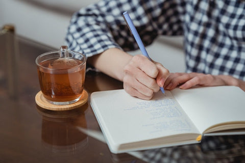 Hombre escribiendo tomando té verde bio