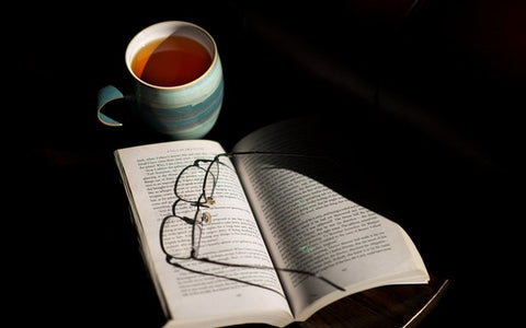 Taza de té blanco bio, libro y gafas