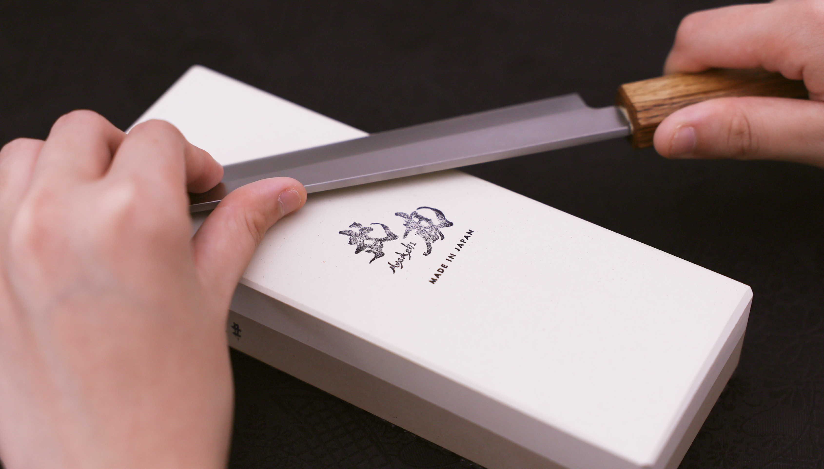 Japanese kitchen knife and sharpening stone against dark background