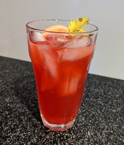 Glass of pink lemonade with ice and a fruit garnish