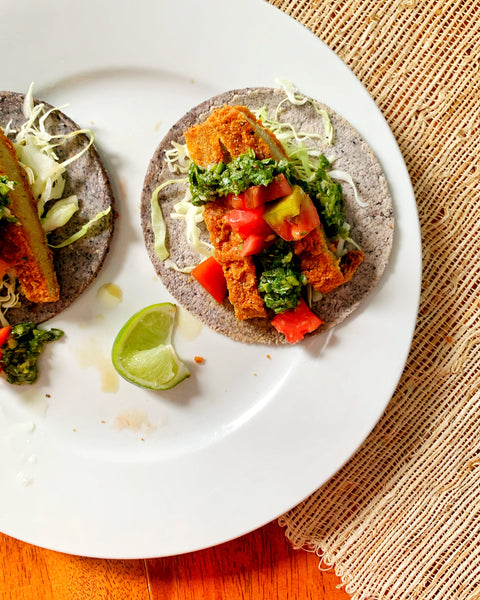 Two seitanic spicy tacos arrange on a white plate