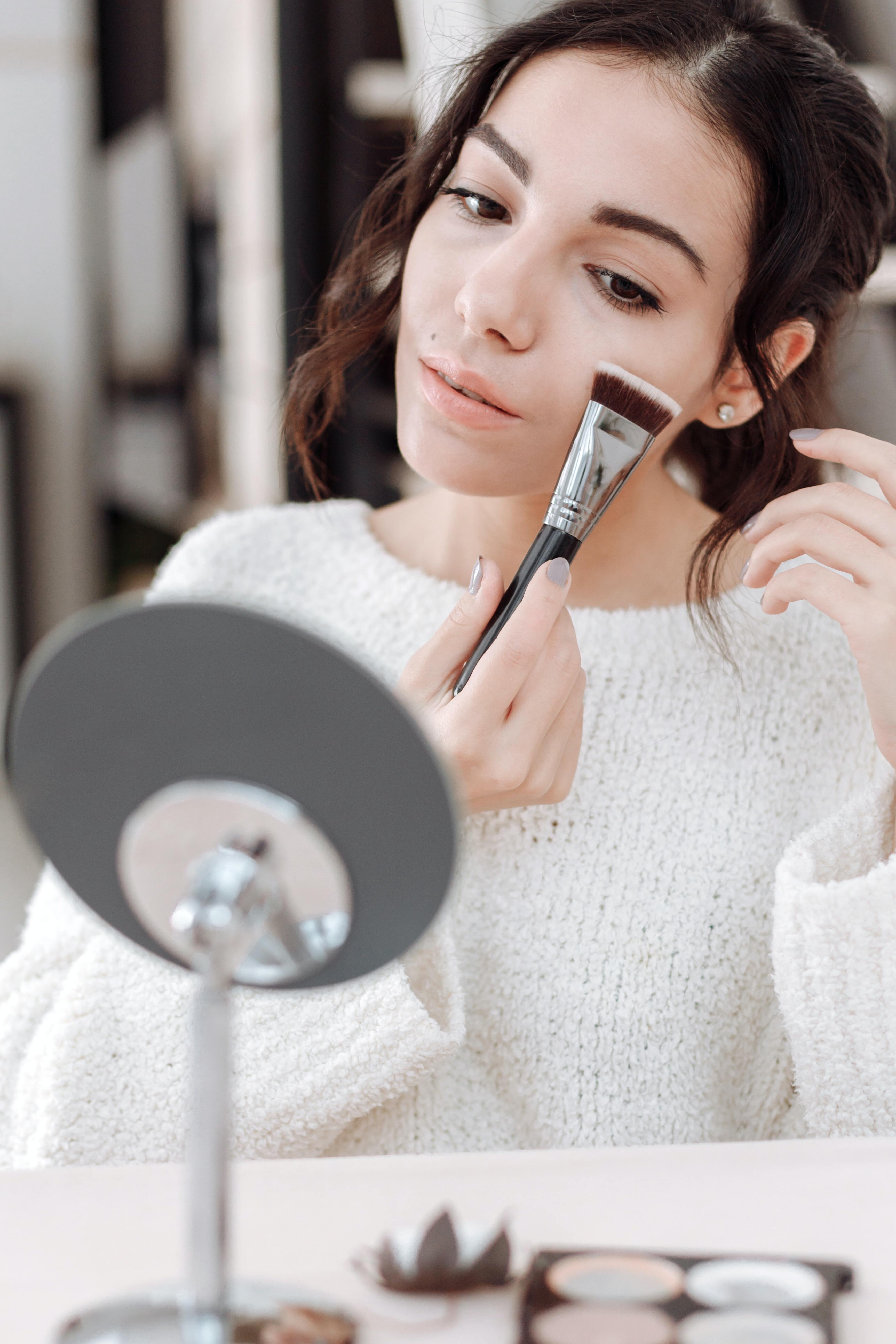 A woman applying a product on her face using a brush