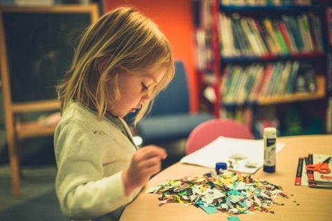 Child crafting with scissors, paper and glue