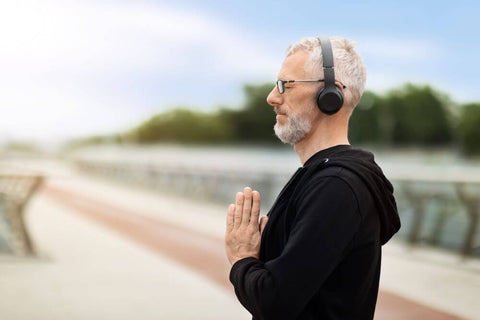 Elderly man meditates outdoors with headset