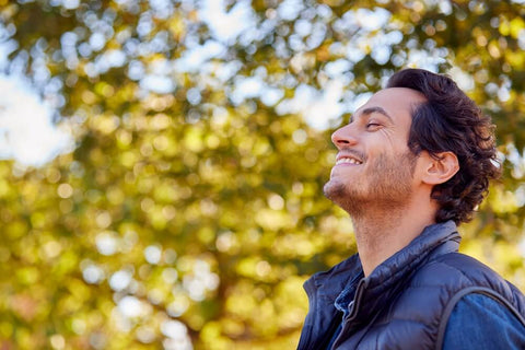 Man looking up with a smile with fall leaves in background