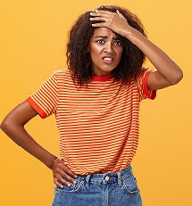 Dark haired woman with hand on forehead looking anxious