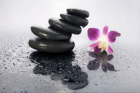 Zen design with stacked black rocks and a purple lily