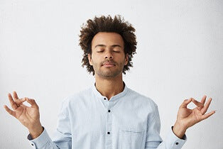 Man with dark hair wearing all white meditating