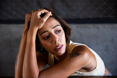 Woman leaning forward with hands on head looking stressed