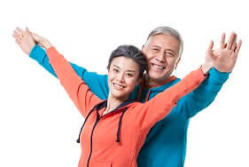 Woman standing in front of man both with arms raised in good health