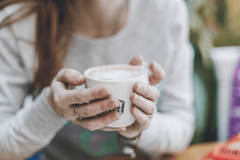 Contemplative woman holding cup with warm coffee