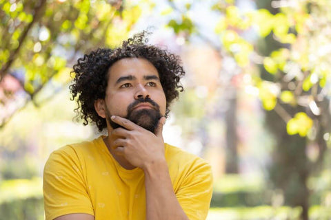 Pensive man hand on chin with yellow t-shirt outdoors